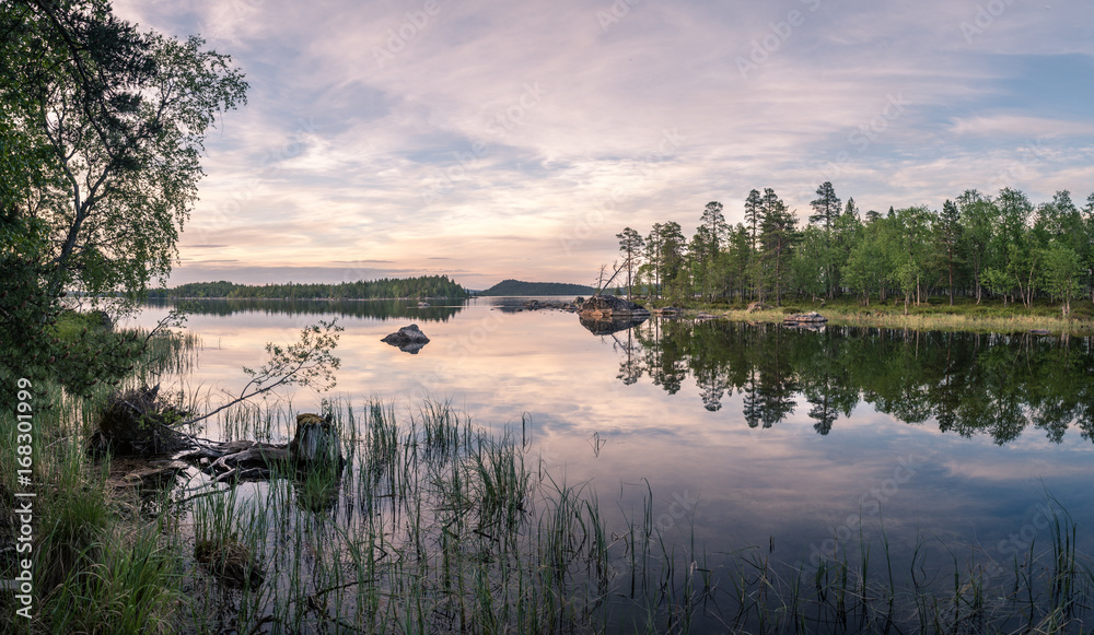 Fototapeta premium Panorama of calm lake at Lapland in midnight sun time. Rocks in front.