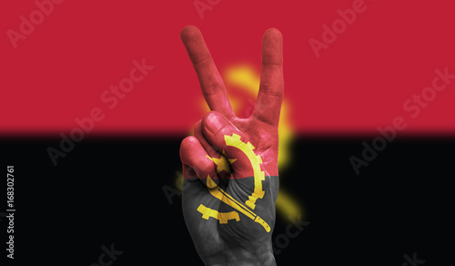 angola national flag painted onto a male hand showing a victory, peace, strength sign photo