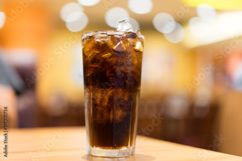 Cool ice soft drink cola carbonated liquid fresh food with soda water, white dish on wooden table with handsome man sitting brown sofa in pizzeria restaurant.