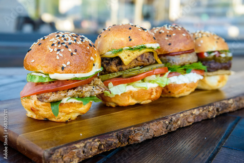 Four burgers on wooden board in restaurant
