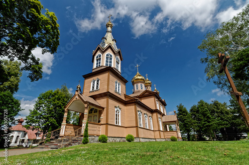 Old wooden church in east of Poland. At the top gold domes and cross.