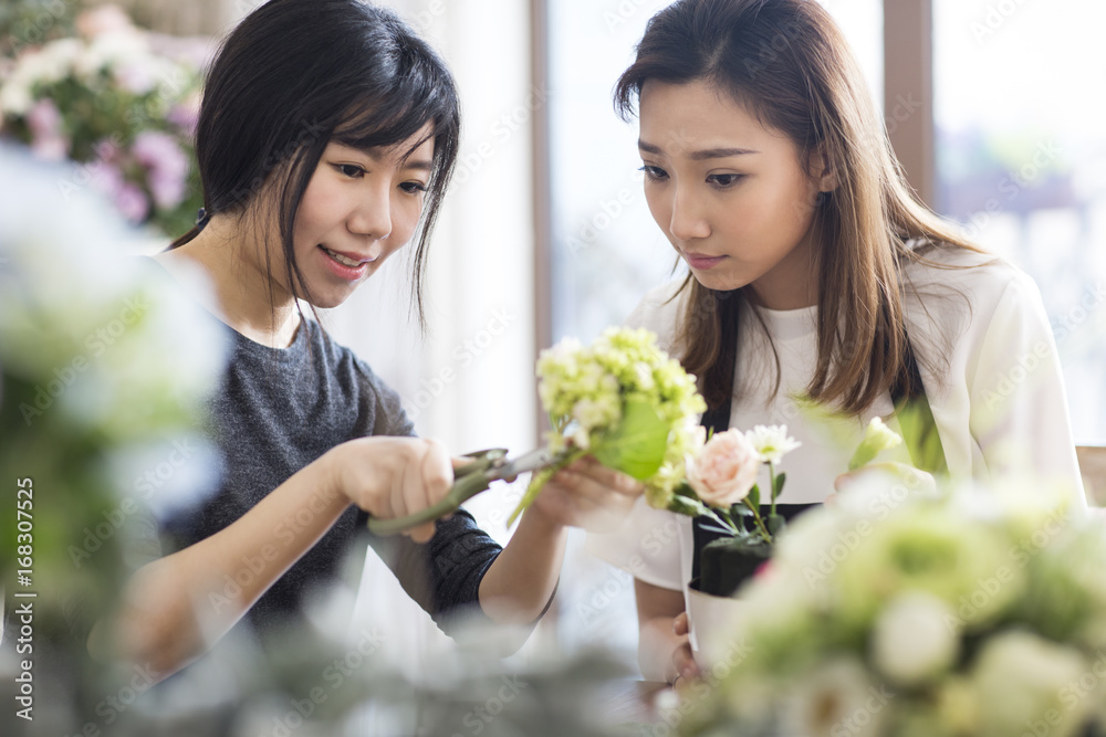 Young woman learning flower arrangement from teacher