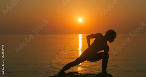 Girl practices yoga near the ocean
