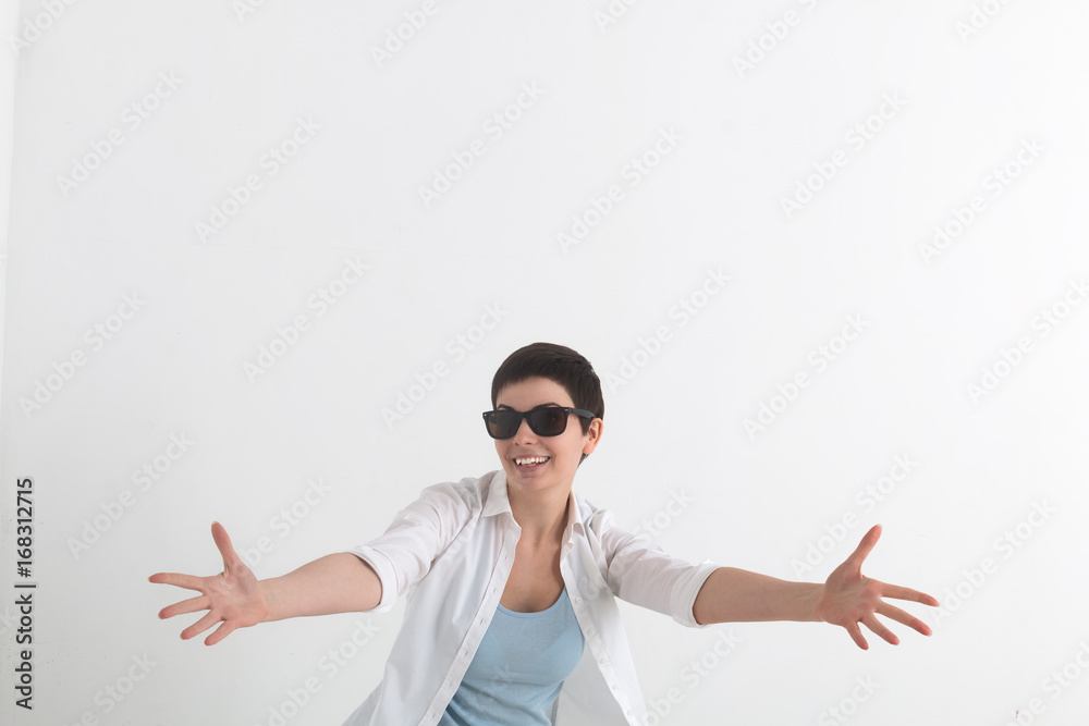 Success positive emotions. Happy young woman in white shirt and sunglasses stretching hands ahead, wanting to hug someone. Success positive emotions. Happy young woman in white shirt and sunglasses stretching hands ahead, wanting to hug someone.