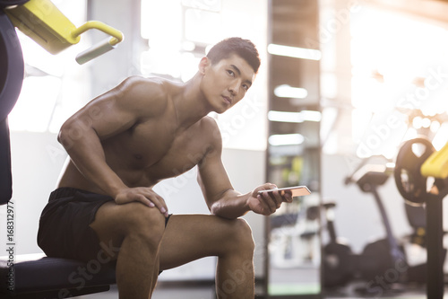 Young man using smart phone in gym