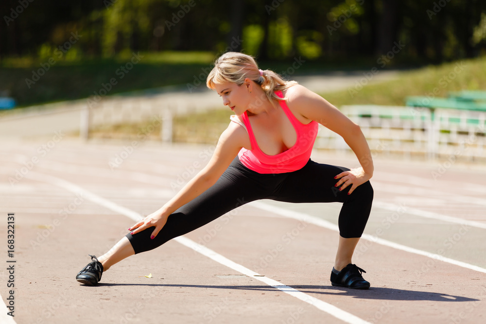 Smiling beautiful sporty young woman working out on road, doing warming up lunge exercise, Extended Side Angle Pose, full length Smiling beautiful sporty young woman working out on road, doing warming up lunge exercise, Extended Side Angle Pose, full length