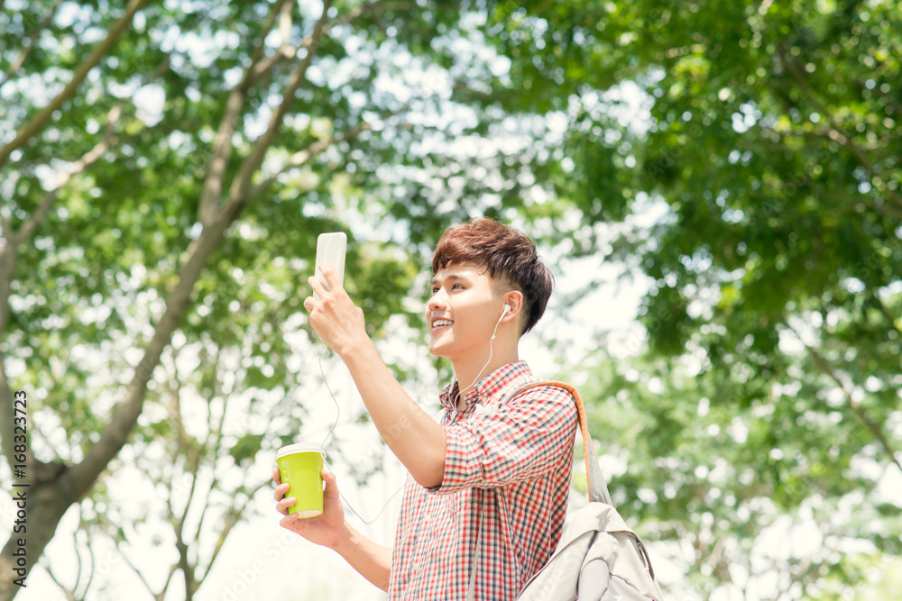 Handsome college student with backpack standing in profile and looking at camera with toothy smile, waist-up portrait Handsome college student with backpack standing in profile and looking at camera with toothy smile, waist-up portrait