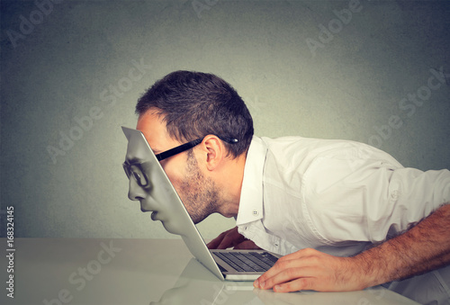 Business man in glasses passing his head through a laptop screen photo