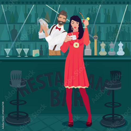 Young and cheerful girl in red dress is standing by the bar counter with a raised cocktail glass and making a selfie photo. Fashionable bartender prepares a cocktail