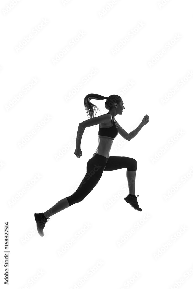 Black silhouette of a girl in sportswear jumping against a white background, studio