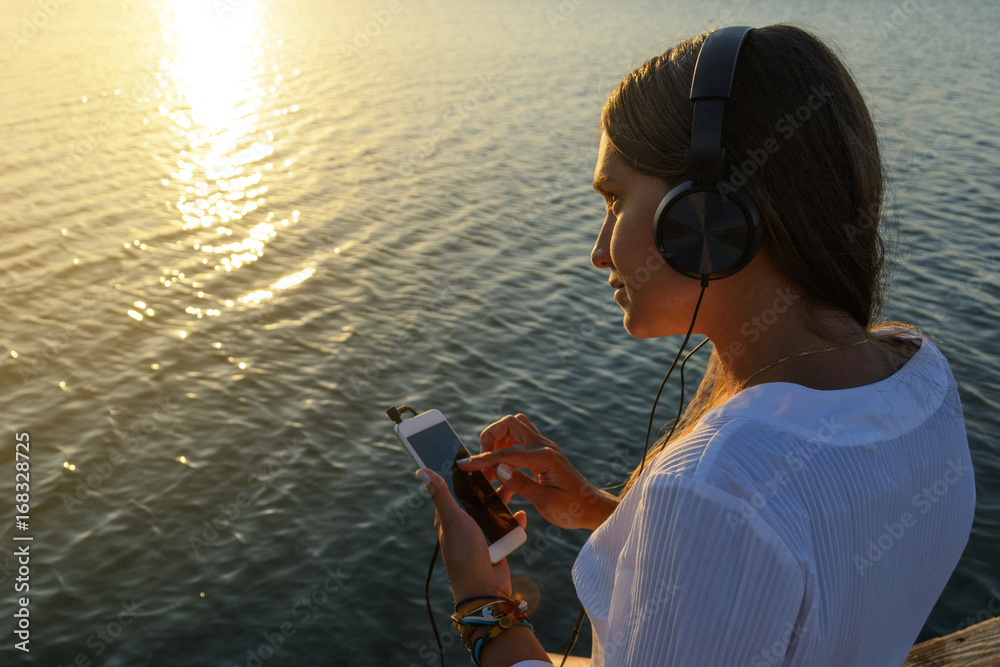 Girl in headphones on a bridge by the sea. Relaxation and concentration