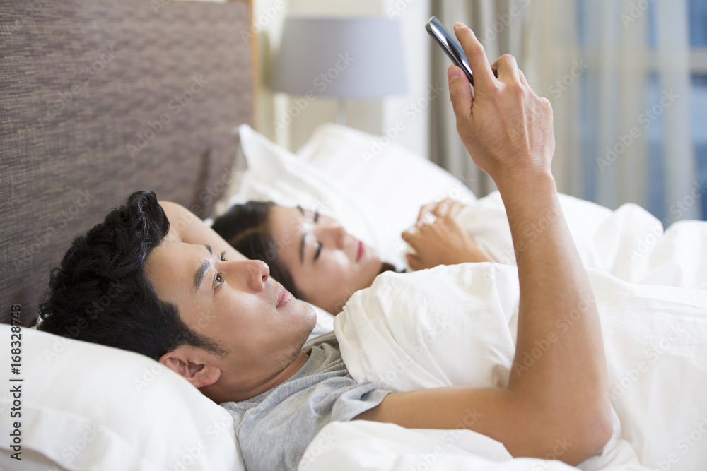 Young husband using smart phone on bed Young husband using smart phone on bed