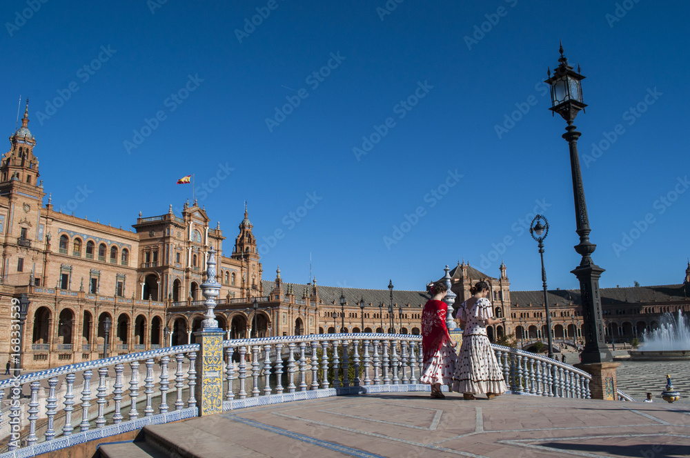 Spagna: ragazze sivigliane di spalle in abiti tipici in Plaza de Espana pronte per la Fiera di Siviglia (Feria de abril) che inizia due settimane dopo la Settimana Santa di Pasqua