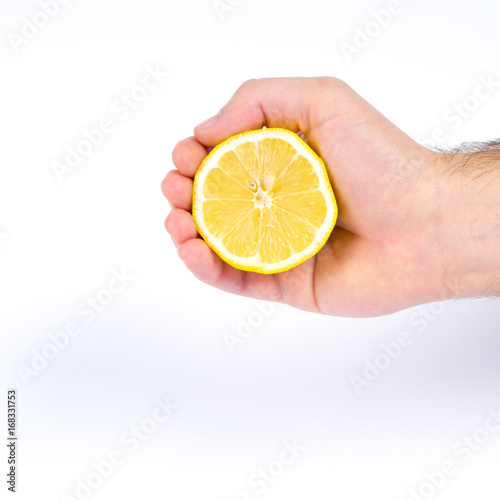 Males hand holding a half lemon and squeeze it with white background