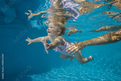 little child learns to swim underwater in the pool