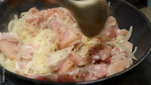 Chicken frying in a pan with onion and spices