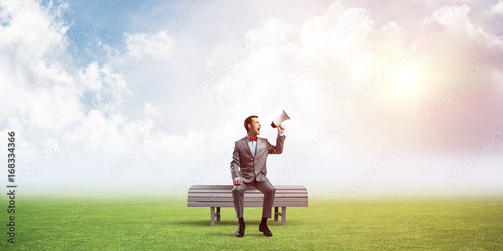Businessman in summer park announcing something in loudspeaker Businessman in summer park announcing something in loudspeaker