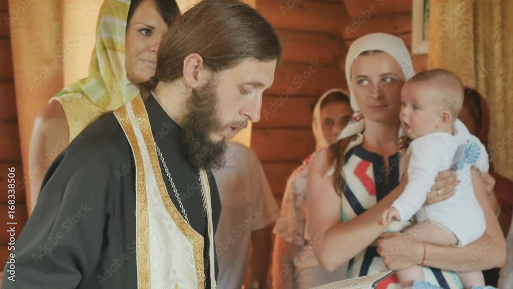 The priest performs a rite of baptism, crossing himself and praying The priest performs a rite of baptism, crossing himself and praying