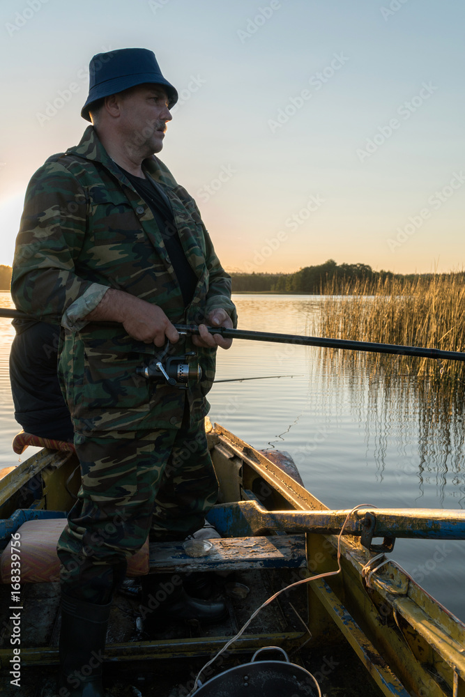 A man is fishing from a boat on sunset A man is fishing from a boat on sunset