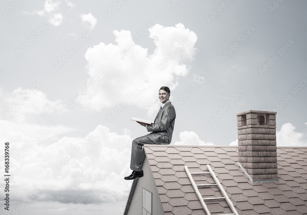Student guy in suit on brick house roof reading book Student guy in suit on brick house roof reading book