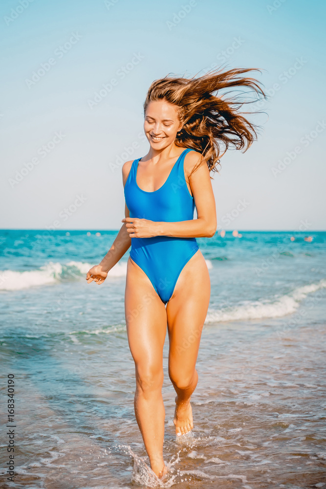 Sexy bikini body woman playful on paradise tropical beach having fun playing splashing water. Beautiful fit body girl on luxury travel vacation.