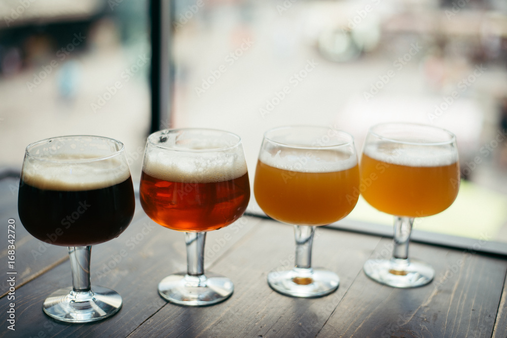 four glasses of beer on wooden table four glasses of beer on wooden table