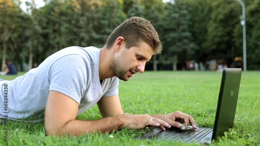 A man in the park is working on a laptop. Mobile office, freelancer. A man in the park is working on a laptop. Mobile office, freelancer.