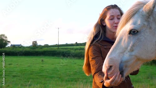 young woman and her horse at sunset in a field