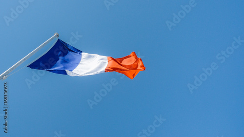 French flag against a blue sky with copy space