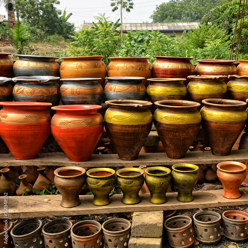Clay pots stacked for sale on African roads. Pottery making place. Local craft market in Africa. Unique handmade colorful ceramic pots. Craftsmanship. African style. © Nataly Reinch