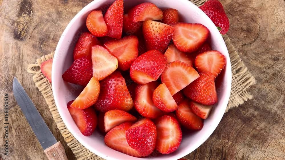 Chopped Strawberries rotating on a wooden plate as seamless loopable 4K UHD footage