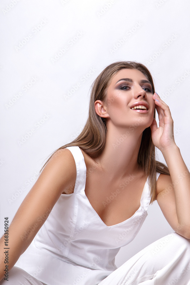 Girl in white clothes posing in the studio on the floor on a white background Girl in white clothes posing in the studio on the floor on a white background