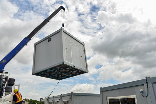 Mobile Crane car on a construction site. Lifts up a temporary office box photo