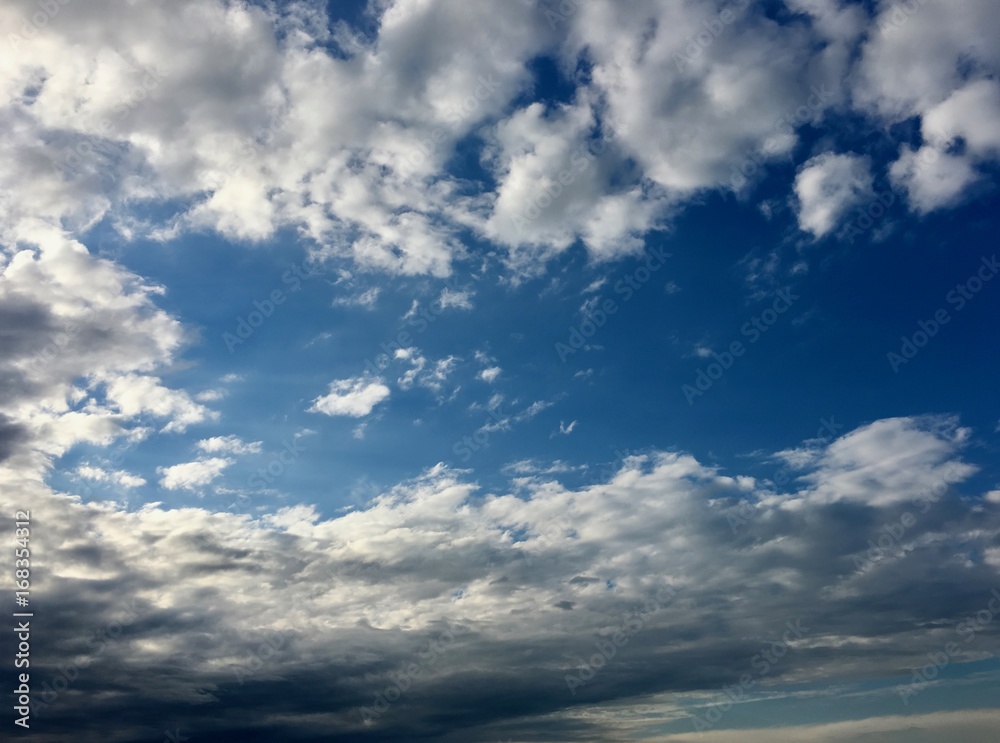 Wide azure evening sky and altocumulus clouds