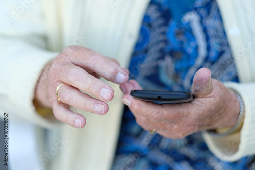 Wrinkled hands of an elderly woman with a mobile phone