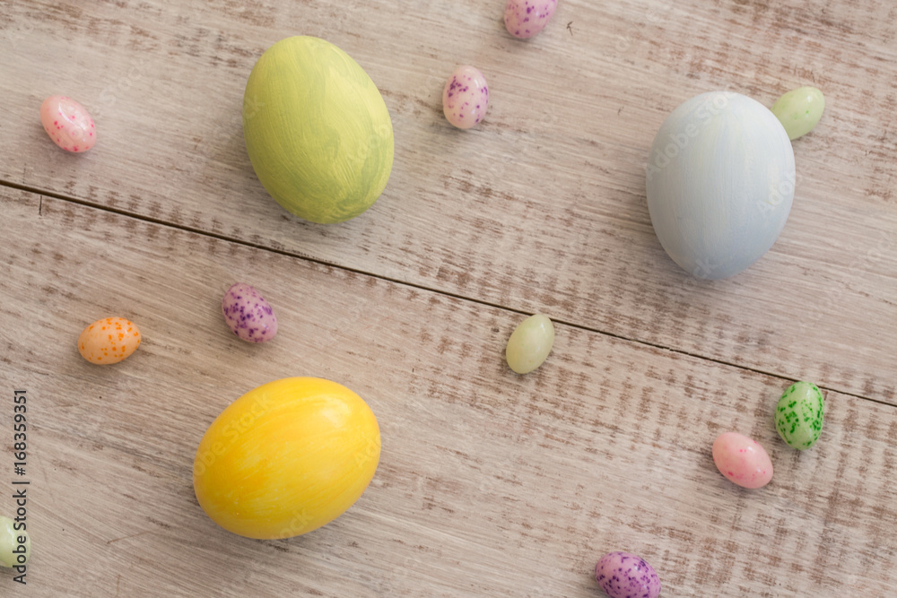 Pastel Colored Easter Eggs and Jelly Beans on White Wood Background Pastel Colored Easter Eggs and Jelly Beans on White Wood Background