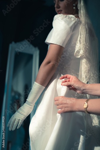 Bilde på lerret Vintage 1940s bride looking over shoulder at seamstress finishing dress