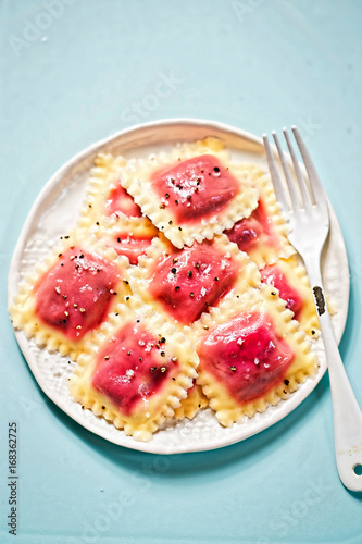 Beetroot ravioli with olive oil on blue surface