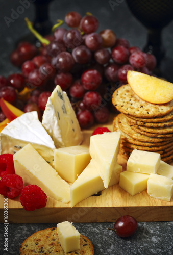 Cheese, crackers and fruits on wooden background