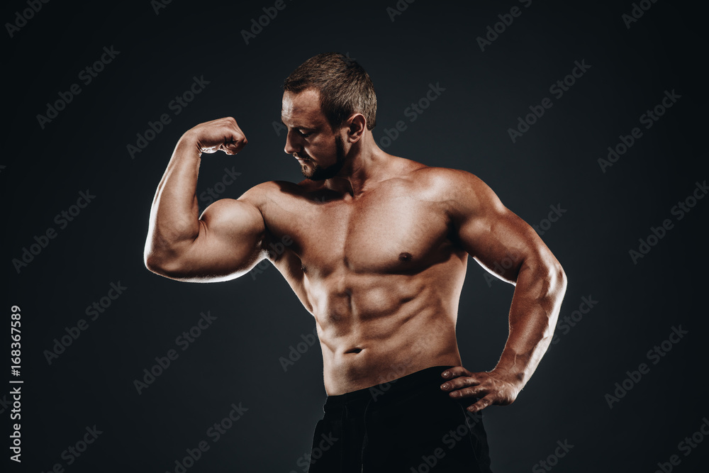 Strong athletic bodybuilder with muscular arm ands fist , perfect abs,  shoulders, biceps, and triceps chest, personal fitness trainer flexing his muscles  Stock Photo