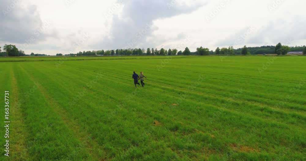 Young couple guy and girl running across the field in slow motion. Aerial footage. Young couple guy and girl running across the field in slow motion. Aerial footage.