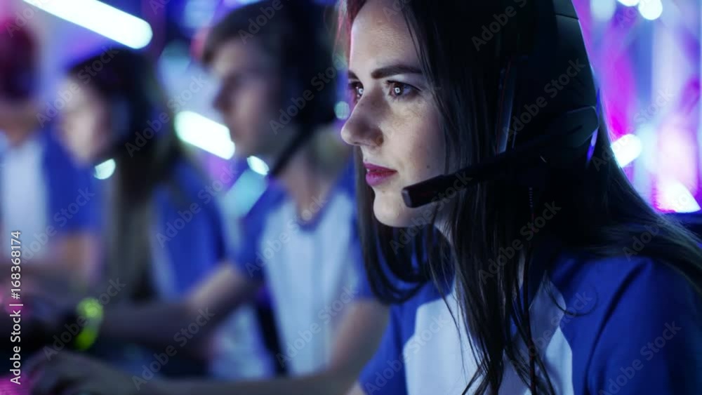 Beautiful Professional Gamer Girl and Her Team Participate in eSport Cyber Games Tournament. She Has Her Headphones and as a Team Leader She Commands Strategical Maneuvers into Microphone. Beautiful Professional Gamer Girl and Her Team Participate in eSport Cyber Games Tournament. She Has Her Headphones and as a Team Leader She Commands Strategical Maneuvers into Microphone.