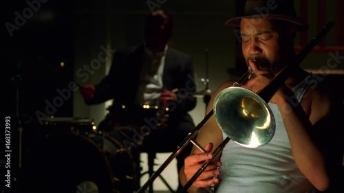 Trombone player in jazz band with drummer in the background.