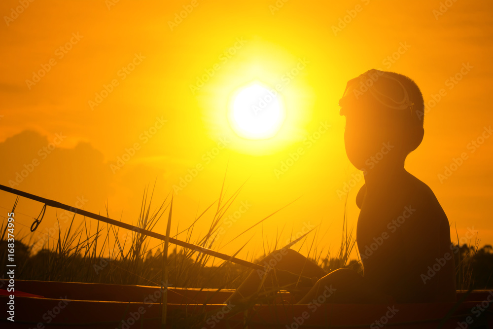 Silhouette of boy catch fish from a boat at sunset,a happy time for the holidays. Silhouette of boy catch fish from a boat at sunset,a happy time for the holidays.