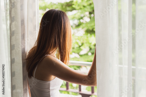 Free Download young asian woman opening curtains in the morning - GFXLoad