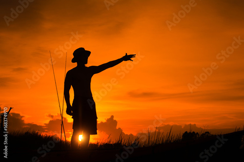 Silhouette of fisherman on the boat pointing with finger in sky. © EsanIndyStudios
