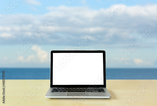 Laptop blank screen on table with sea and sky background © topzafoto