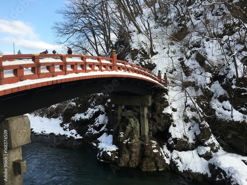 Shinkyo red bridge under white fresh snow over Daiya river in Nikko Japan photo