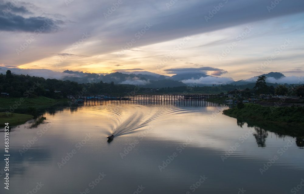Fototapeta premium The atmosphere the morning at Sangkhlaburi District, a small boat travel on the river in beautiful nature forest and mountain landscape