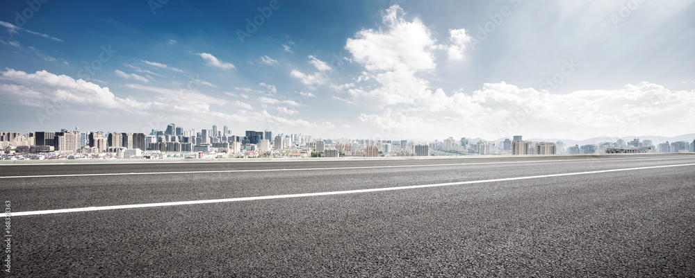 empty road and cityscape of modern city against cloud sky - obrazy, fototapety, plakaty 